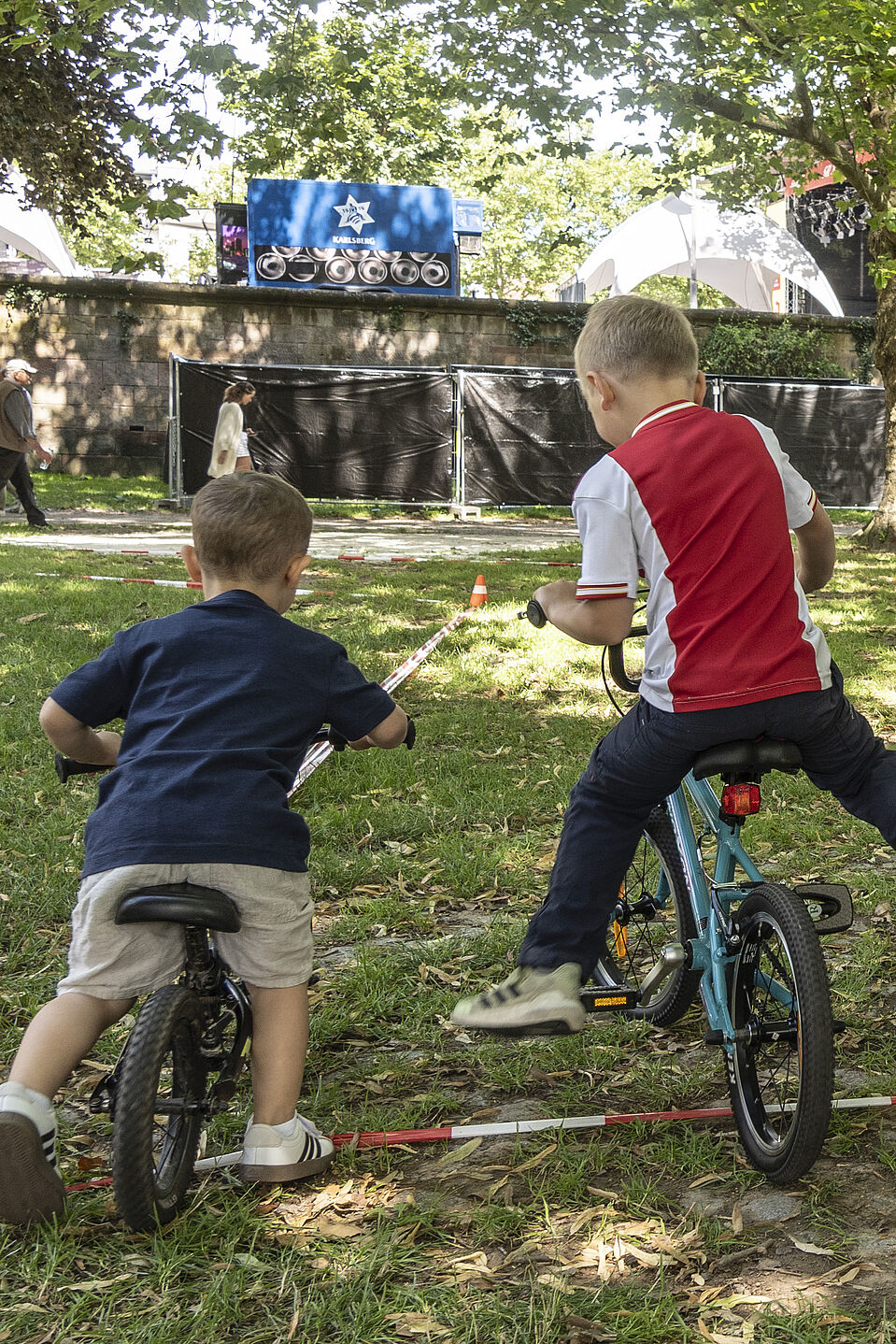 ADFC Saar Fahrradaktion Altstadtfest Kinder mit Lauf- und Fahrrädern auf einer Wiese, angewiesen durch einen Erwachsenen.